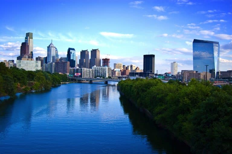 USA Reisen - Die Skyline von Philadelphia, Pennsylvania, mit einem Fluss im Hintergrund.